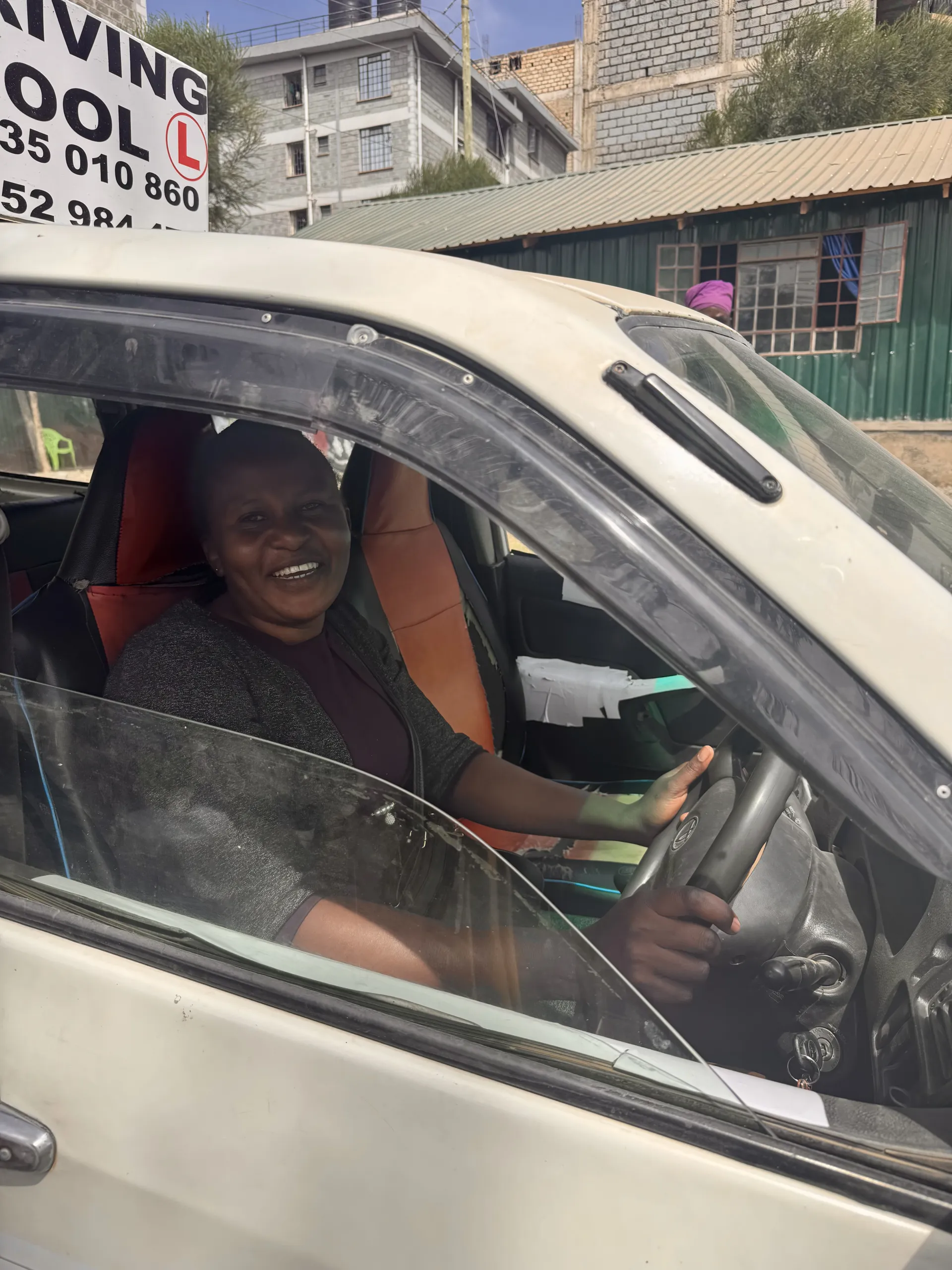 A woman smiling from the driver's seat during practical training